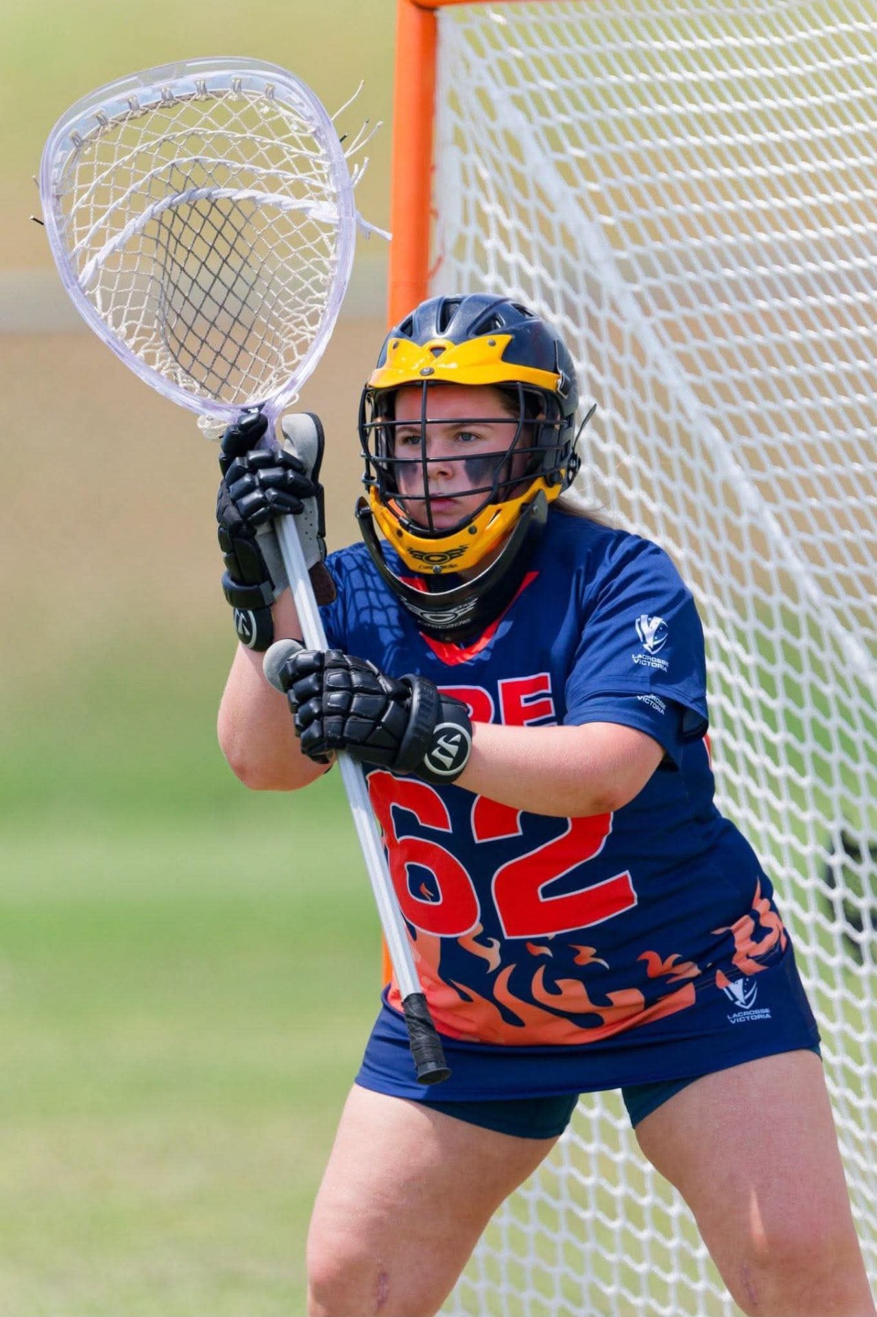 Ivy in front of the goal in her FIRE #62 jersey, stick up and ready for a shot.