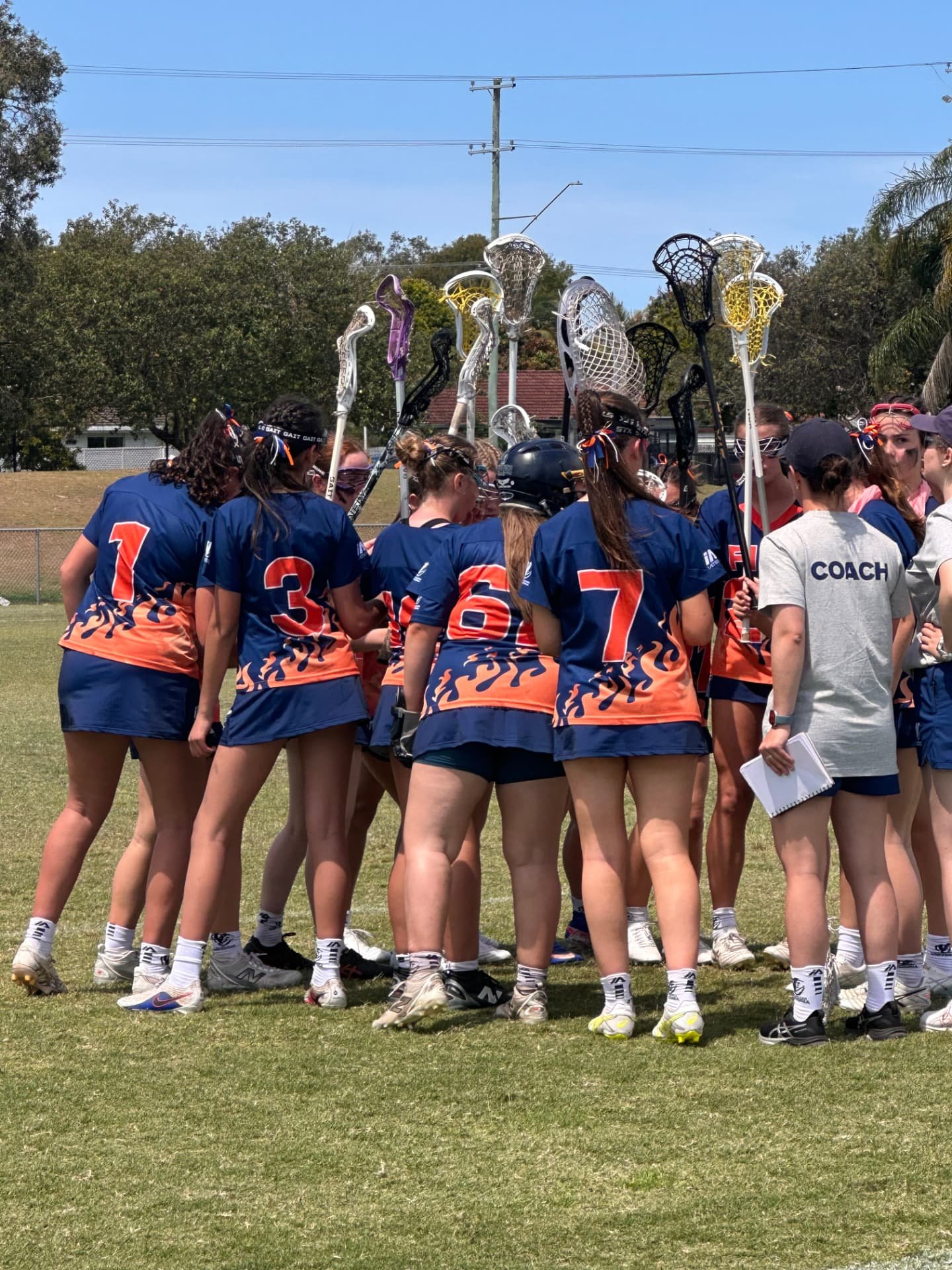 FIRE players gathered in a huddle with sticks raised.