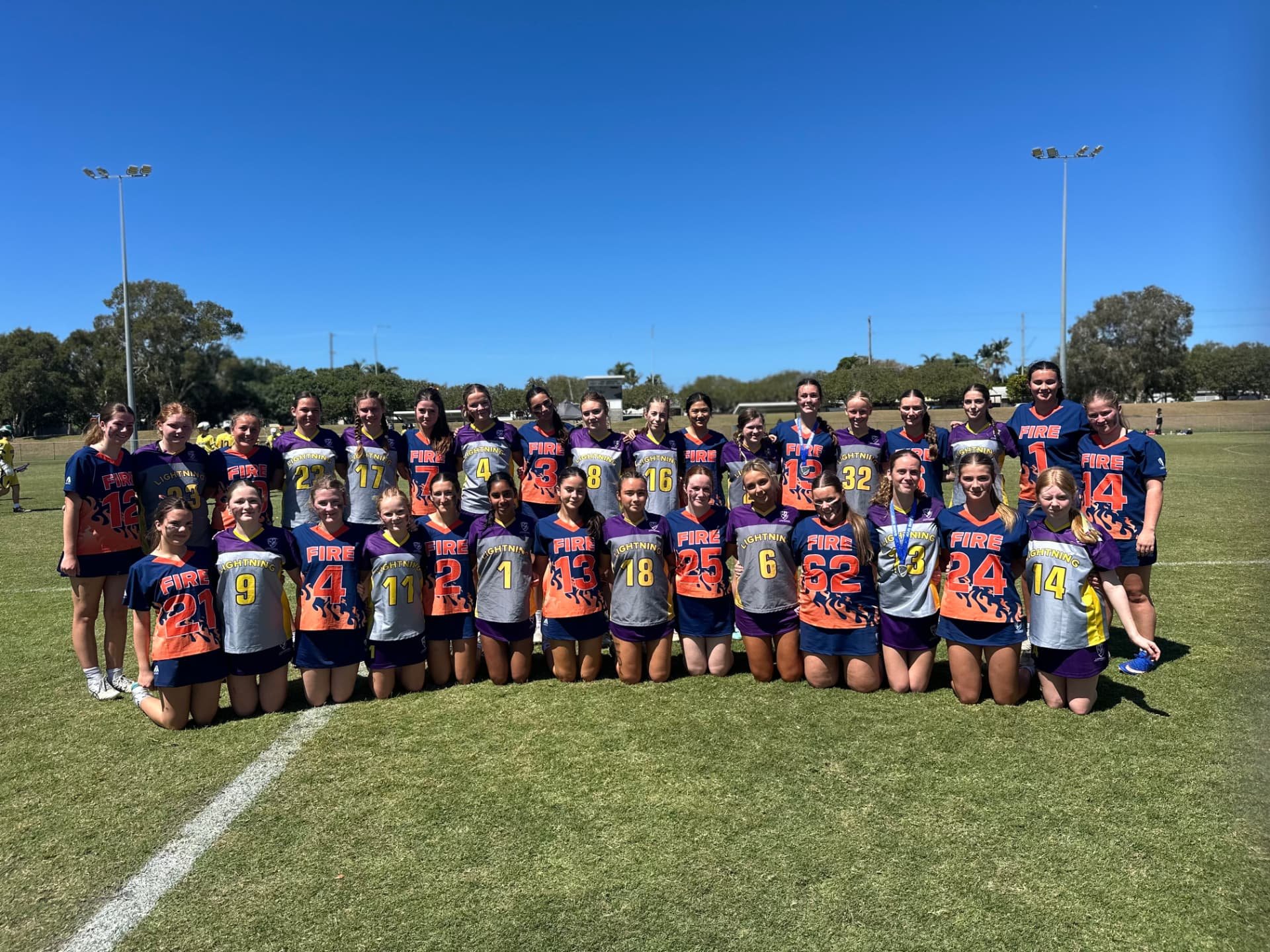 FIRE players posing together with another team on the field for a group photo.