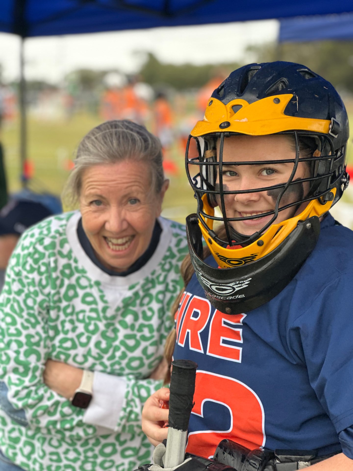 Ivy, in her goalie helmet, smiling with a supporter.